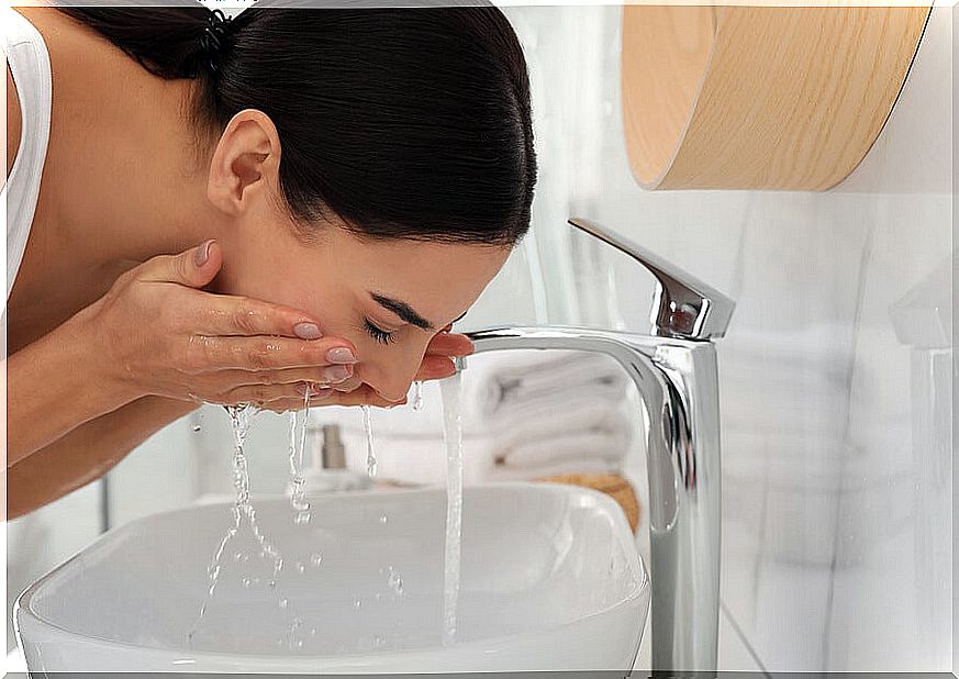 Woman washing her face in the sink.